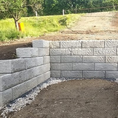 Stützmauer aus hellen Betonblöcken sichert den Hang neben einem Neubau – stabile Lösung für Grundstück in Hanglage
