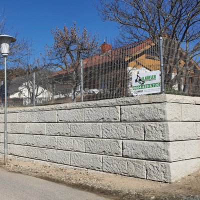 Helle Betonsteine mit stabilem Gitterzaun sichern den Garten entlang der Straße