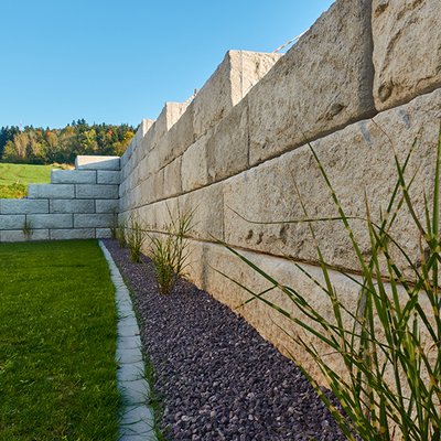 Solide Stützmauer mit stufigem Verlauf sichert den Hang – ideal für moderne Gärten