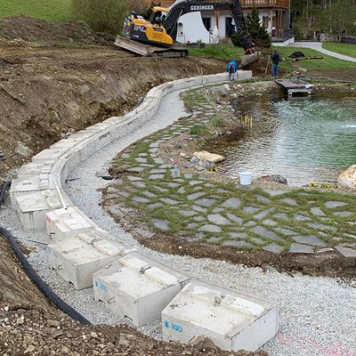 Gebogene Betonblöcke werden entlang des Badeteiches als stabile Hangabsicherung gesetzt