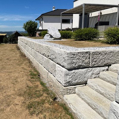 Moderne Gartenmauer aus Beton mit eingebautem Treppenaufgang – ideal bei Hanglage