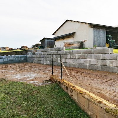 Langlebige Stützmauer aus Betonblöcken schützt Hofbereich bei Hanglage