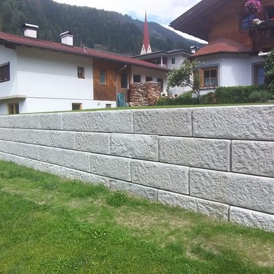 trukturierte Betonsteine bilden eine gleichmäßige Gartenmauer – erweitert die nutzbare Fläche auf Hanggrundstücken