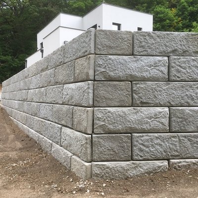 Massive Betonmauer stützt den Garten und schafft eine neue, ebene Fläche