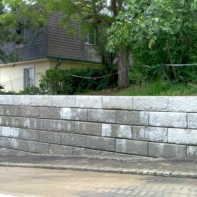 Neue Beton-Stützmauer entlang einer schmalen Straße in Wien – kompakte Lösung zur Hangabsicherung im Stadtbereich
