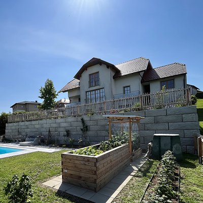 Gerade Stützmauer bringt Struktur in den Hang und lässt Platz für Hochbeete