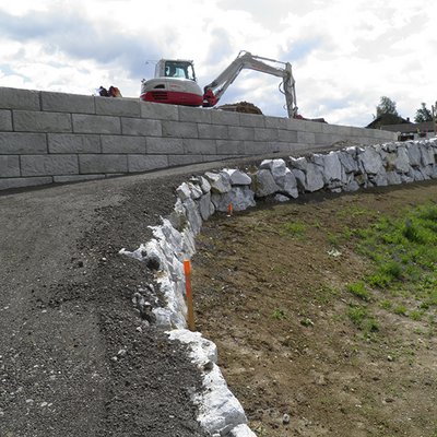 Neue Stützmauer aus Betonsteinen begleitet den Fußweg und stützt das Gelände sicher ab