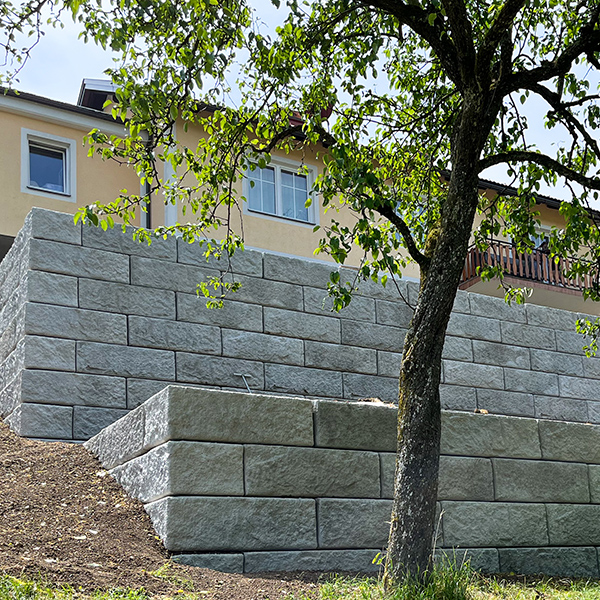 Mehrere gestufte Betonmauern am Hang – Grundstück am Einfamilienhaus in nutzbare Ebenen unterteilt